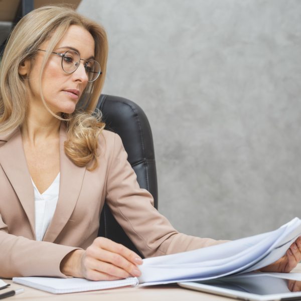 blonde-young-businesswoman-reading-documents-workplace
